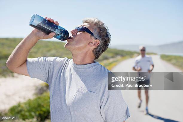 thirsty man drinking water from water bottle - refresh stock pictures, royalty-free photos & images