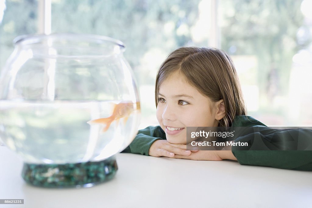 Girl looking at goldfish in bowl