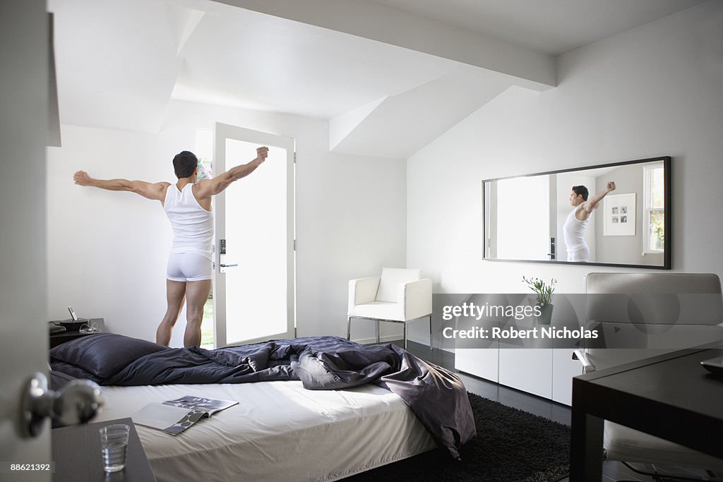 Man stretching in bedroom in morning