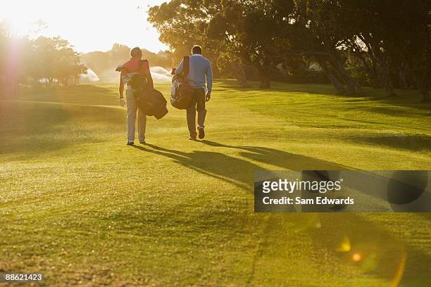 männer tragen golf taschen auf den golfplatz - golf stock-fotos und bilder