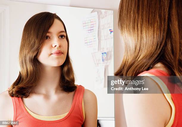 girl looking at reflection in mirror - girl in mirror stock pictures, royalty-free photos & images