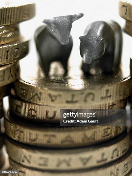 bull and bear figurines on top of stack of pound coins - bull bear stock pictures, royalty-free photos & images