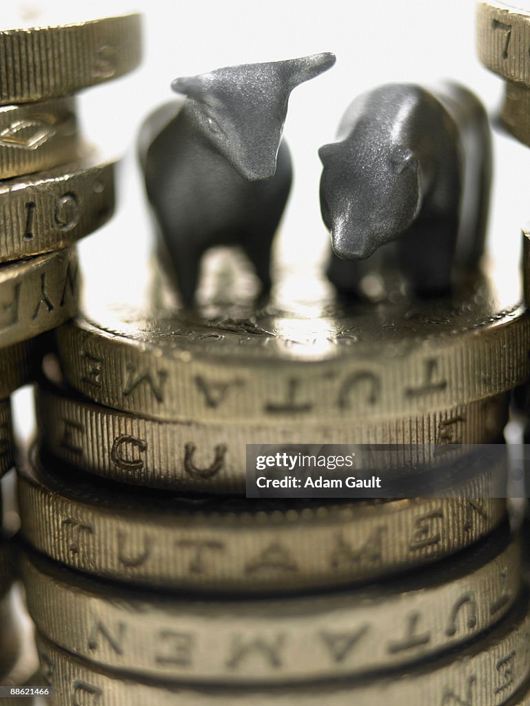 Bull and bear figurines on top of stack of pound coins