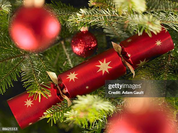 close up of christmas cracker and ornaments on tree - christmas cracker stock pictures, royalty-free photos & images