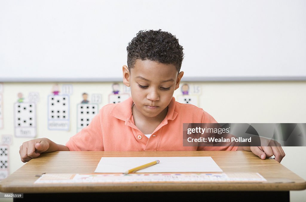 Frustrated boy looking at test in classroom