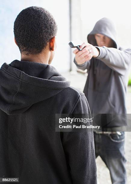 attacker pointing gun at man - paul gun stock pictures, royalty-free photos & images