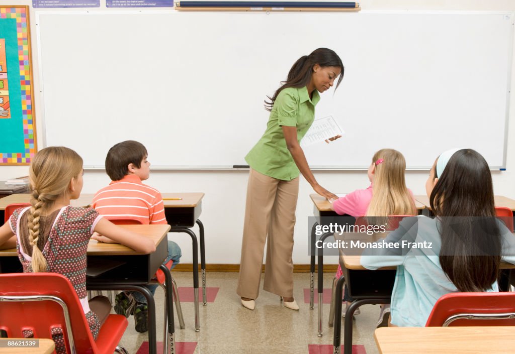 Teacher passing out tests to students in classroom