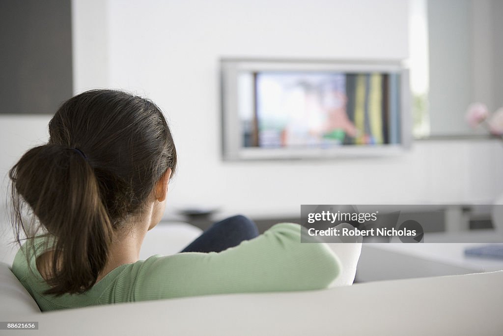 Teenage girl watching television in living room