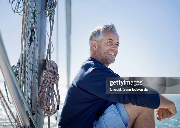 man sitting on deck of boat - sail boat deck stock pictures, royalty-free photos & images