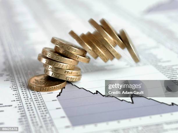 stack of british pound coins falling on list of share prices - pond stockfoto's en -beelden