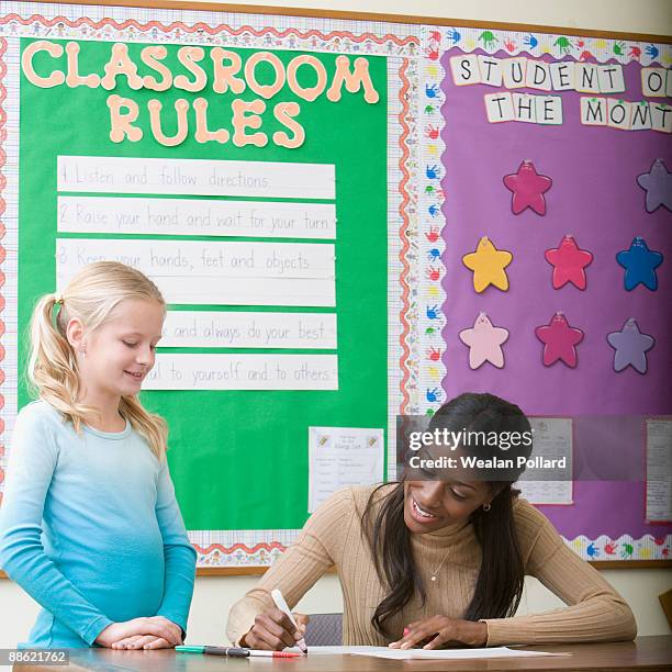 teacher grading girls paper in classroom - pollard review stock pictures, royalty-free photos & images