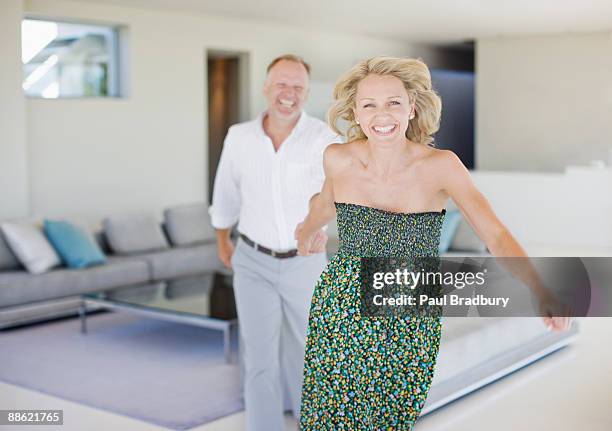 woman pulling  husband across living room - woman home run stock pictures, royalty-free photos & images