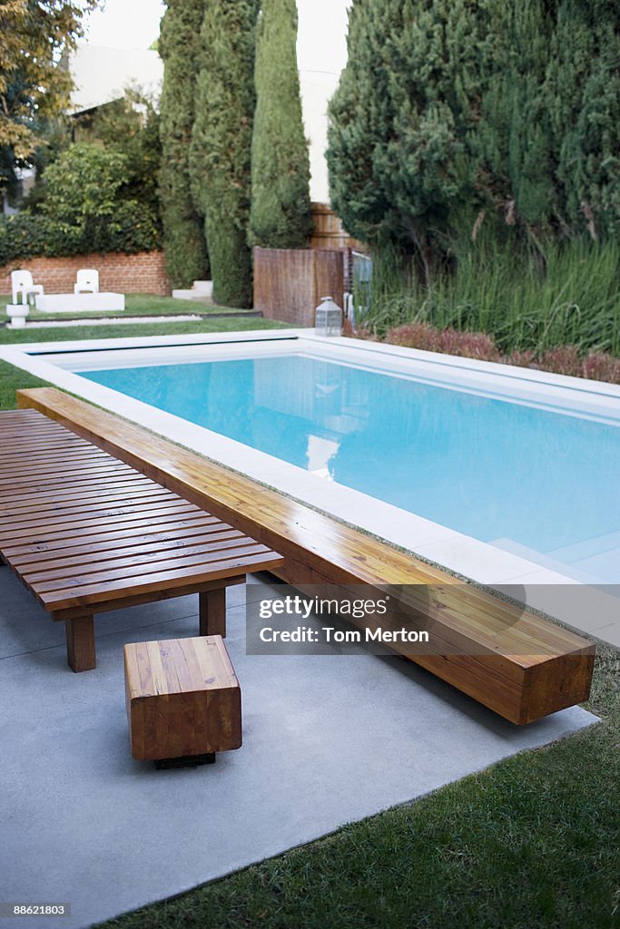 Modern wooden lounge chair next to swimming pool