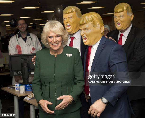 Britain's Camilla, Duchess of Cornwall poses with members of staff wearing Donald Trump masks during her visit to the offices of city traders ICAP on...