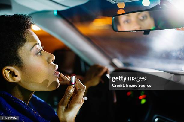 woman putting on lipstick in car - make up looks stock pictures, royalty-free photos & images