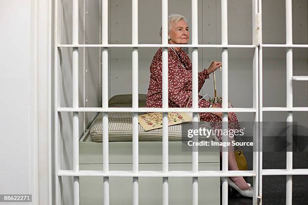 senior woman in prison cell - gefängniszelle stock-fotos und bilder