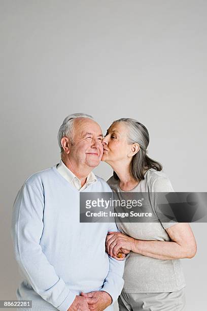 woman kissing husband - senioren koppel studio stockfoto's en -beelden
