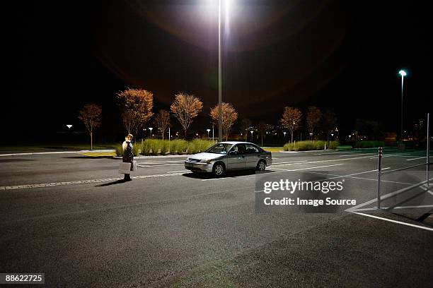 woman in alone in parking lot - car lot stock-fotos und bilder