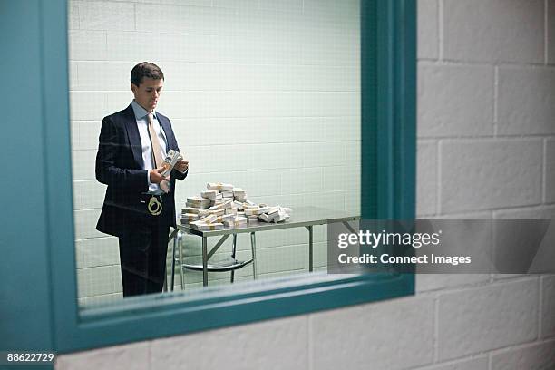 detective looking at money - police station foto e immagini stock