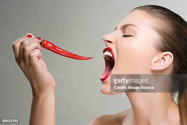 woman biting a red chili pepper - female eating chili bildbanksfoton och bilder