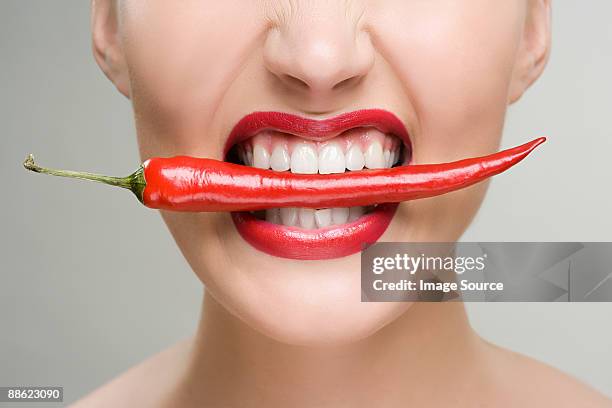 woman with a red chili pepper between her teeth - chili woman ストックフォトと画像