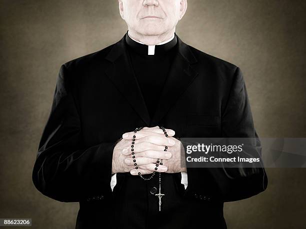 a priest holding prayer beads - catholicism stock-fotos und bilder