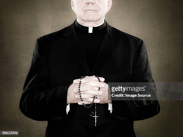 a priest holding prayer beads - katholicisme stockfoto's en -beelden