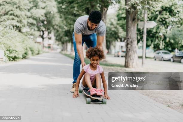 happy african ethnicity family having fun in the park - father longboard stock pictures, royalty-free photos & images