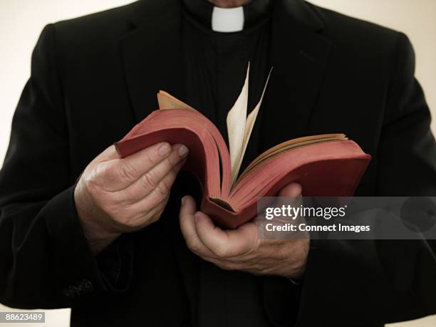 priest holding a bible - priesterkragen stock-fotos und bilder
