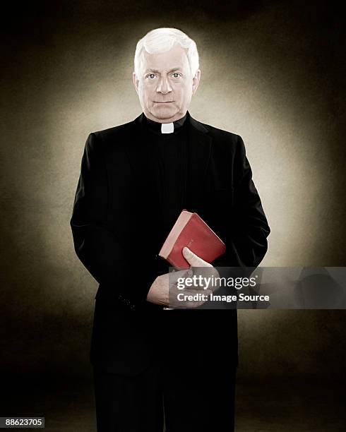 portrait of a priest holding a bible - cuello clerical fotografías e imágenes de stock