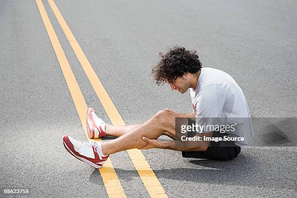 runner with injured leg - injured street stockfoto's en -beelden