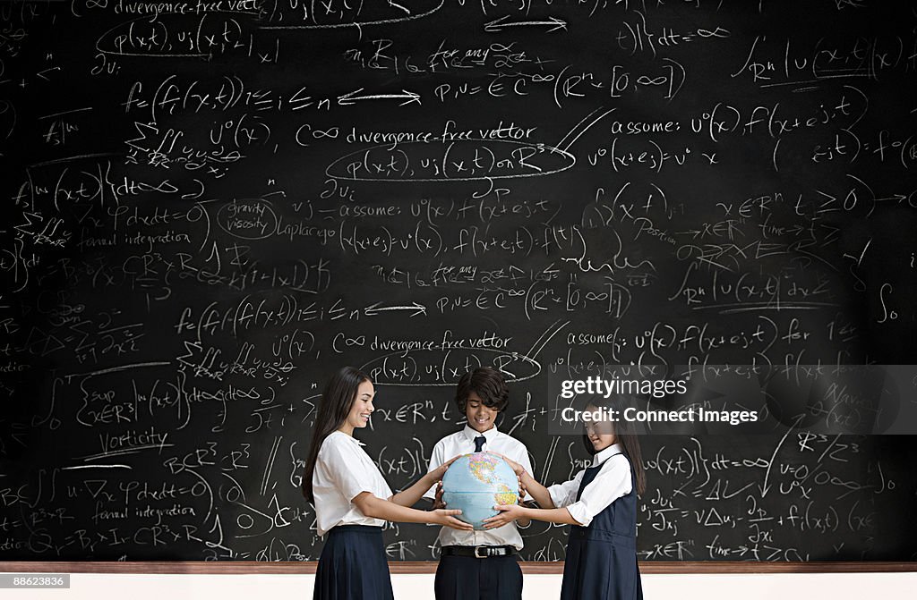 Students with globe in front of blackboard