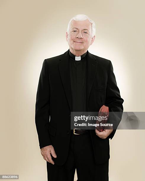 portrait of a priest holding a bible - priest collar stock pictures, royalty-free photos & images