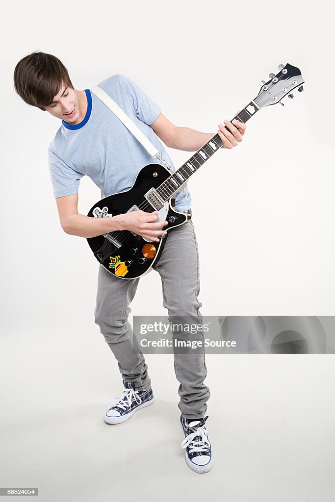 A teenage boy playing a guitar