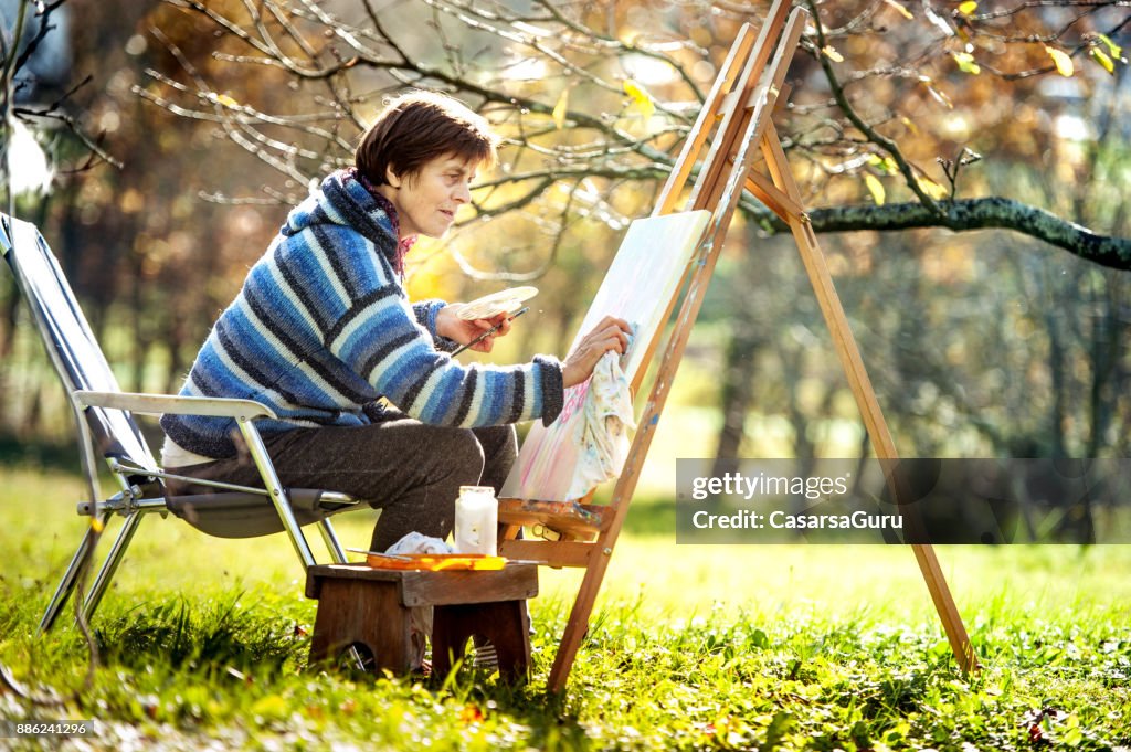 Senior Woman Artist Painting Artwork on Canvas
