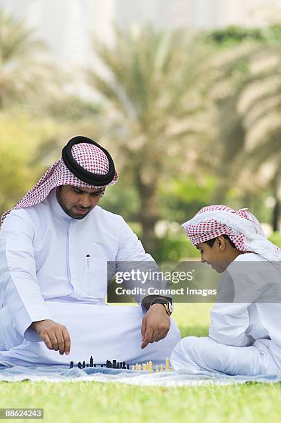 a father and son playing chess in a park - kaffiyeh stock pictures, royalty-free photos & images