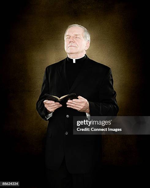 a priest holding a bible - priest collar stock pictures, royalty-free photos & images