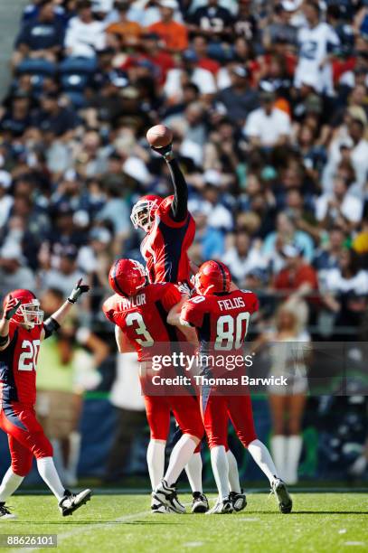 football team celebrating on field in stadium - jogador de futebol americano imagens e fotografias de stock