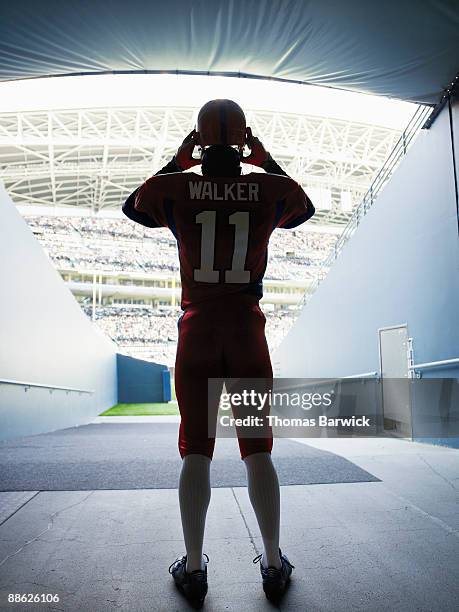 professional football player putting on helmet - american football player back stock pictures, royalty-free photos & images