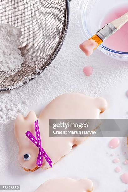 easter bunny shaped biscuits getting iced - schuimspatel stockfoto's en -beelden