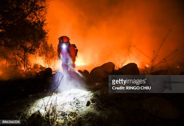 Firefighters battle a wildfire as it burns along a hillside near homes in Santa Paula, California, on December 5, 2017. Fast-moving, wind-fueled...