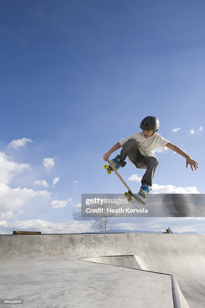 A young male catches some air in a skate park.