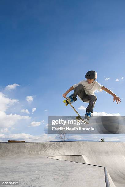 a young male catches some air in a skate park. - skateboard stockfoto's en -beelden