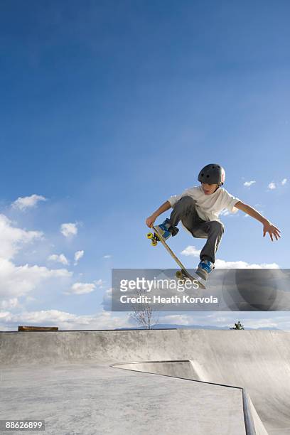 a young male catches some air in a skate park. - skating stock pictures, royalty-free photos & images
