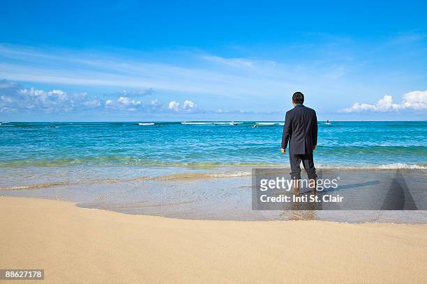man in suit standing on beach looking at ocean - ankle deep in water stock pictures, royalty-free photos & images