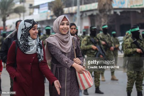 Palestinian women watch as fighters from the Ezzedine al-Qassam Brigades, the armed wing of the Palestinian Hamas movement, march past in the...