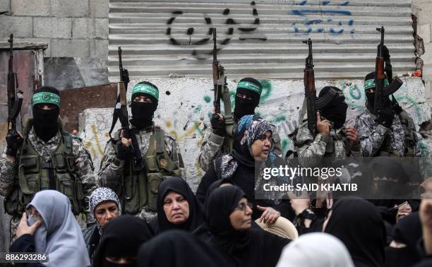 Palestinian women watch as fighters from the Ezzedine al-Qassam Brigades, the armed wing of the Palestinian Hamas movement, take part in a military...