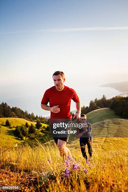 man and woman running up grassy trail. - couple running stock pictures, royalty-free photos & images