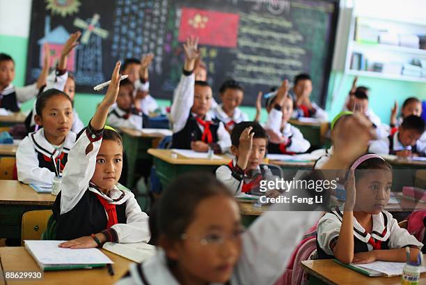 Children raise their hands to answer a question during a Tibetan language class at the Lhasa Experimental Primary School on June 19, 2009 in Lhasa,...