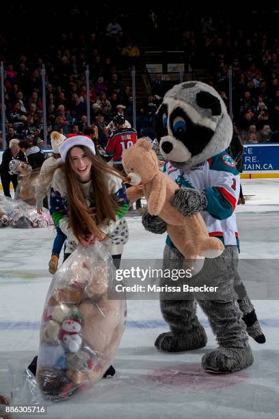 Rocky Raccoon, the mascot of the Kelowna Rockets has a teddy bear fight on the ice with a volunteer cleaning up from the annual teddy bear toss...